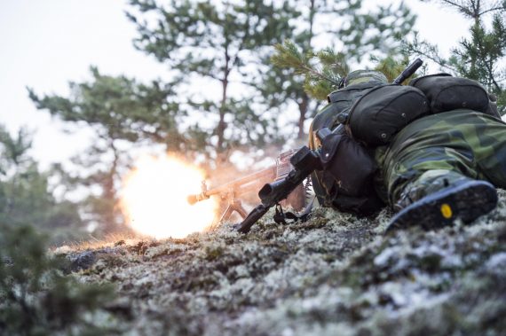 Kulspruteskytt bekämpar fienden, på ryggen har han sin skadade stridsparskamrats AK5C.