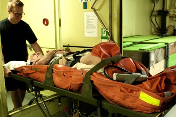 Det behövs hjälp av övriga besättningen för att förflytta båren med patienten genom fartyget. Foto Anders Kallin/Försvarsmakten