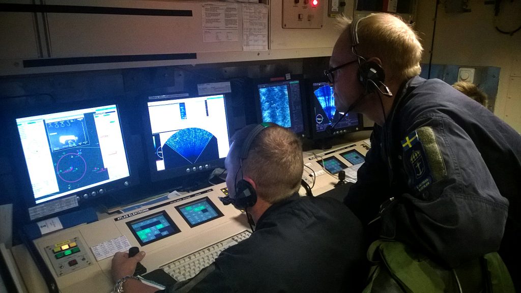 Vaktchefen och UsO (Undervattenstrids Officer) manövrerar fartygets ROV (Remotely Operated Vehicle) med sprängladdning fram till minan inför sprängning. 