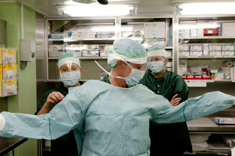 Carlskronas operationsassistenter hjälper operationssjuksköterskan Kristina Forslund med påtagande av operationskläder. Foto: Anders Kallin/Försvarsmakten